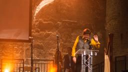 Man in yellow shirt making a speech on stage